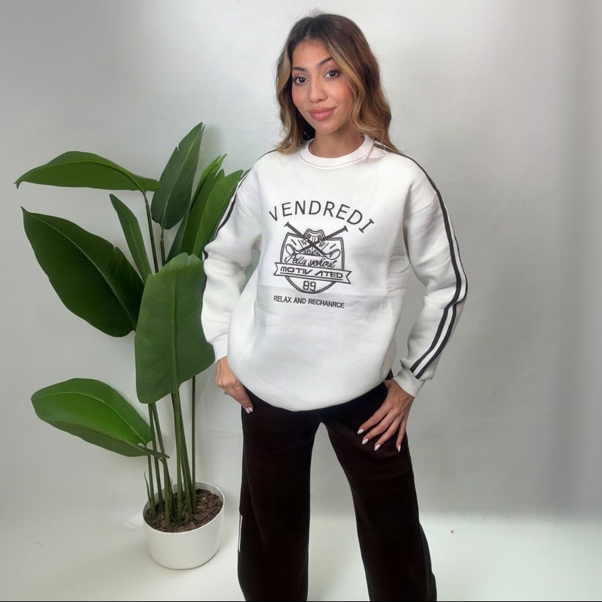 Woman in a white tiger crest varsity sweatshirt with brown wide leg pants, hands on hips