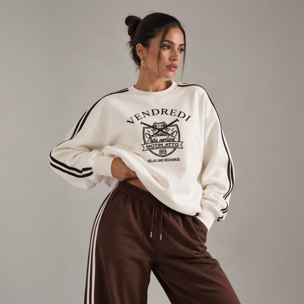 Close up of a white varsity print sweatshirt with brown sleeve stripes and brown drawstring pants