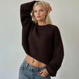 Cropped dark brown sweater in chunky rib knit, wide balloon sleeves, arm raised pose