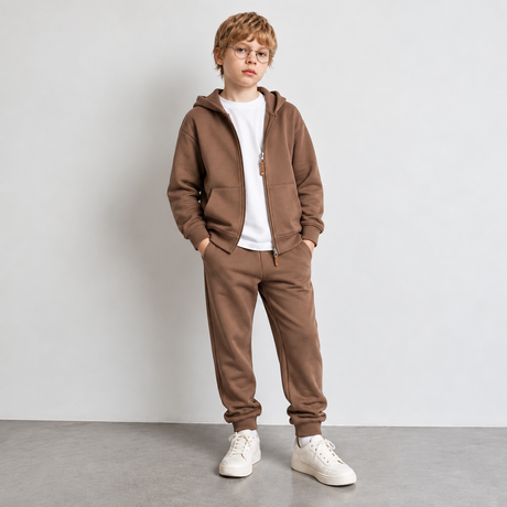 Boy in glasses wearing a brown zip hoodie and joggers over a white tee