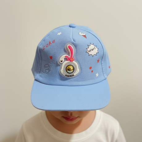 Light blue kids cap with a soft bunny patch and playful doodles across the crown, worn by a child