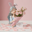 Silver haired figure in grey bunny ears cradling a pink cone of roses, petals scattered