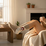 Person sitting in a cozy living room with feet up wearing cozy bunny winter socks and holding a mug