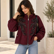 Woman in a burgundy zip jacket with black beaded leaf sprays, balloon sleeves and a lace trimmed hem
