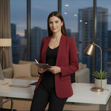 Burgundy blazer worn open at an office desk with a black top and a tablet in hand