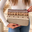 Beige clutch bag with a burgundy geometric braid, beige pom poms, red beads and fringe