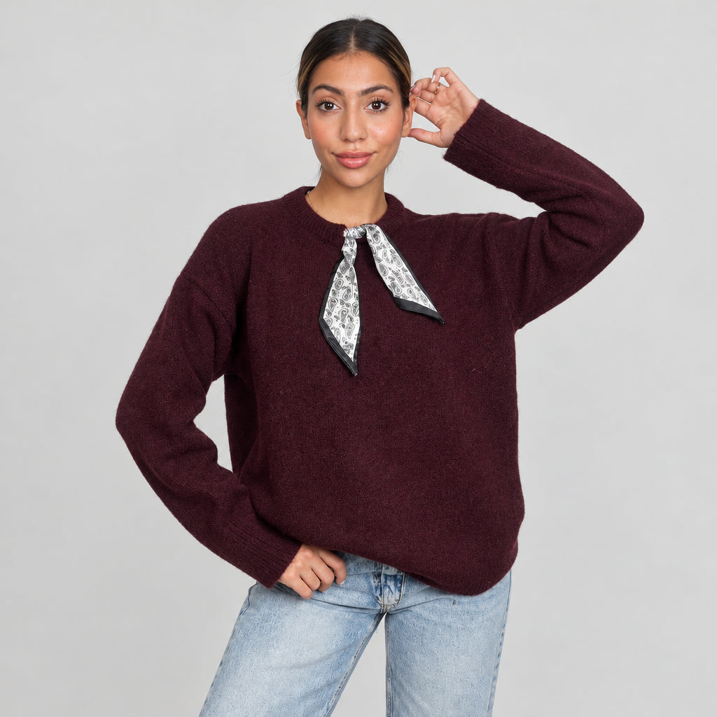Woman in a plum burgundy knit top with a silver printed scarf tie at the collar