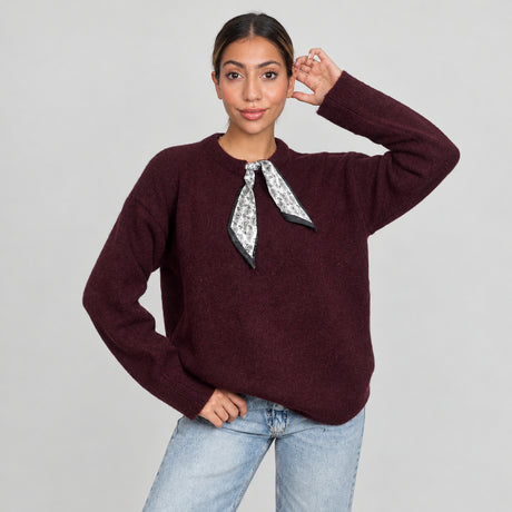 Woman in a plum burgundy knit top with a silver printed scarf tie at the collar