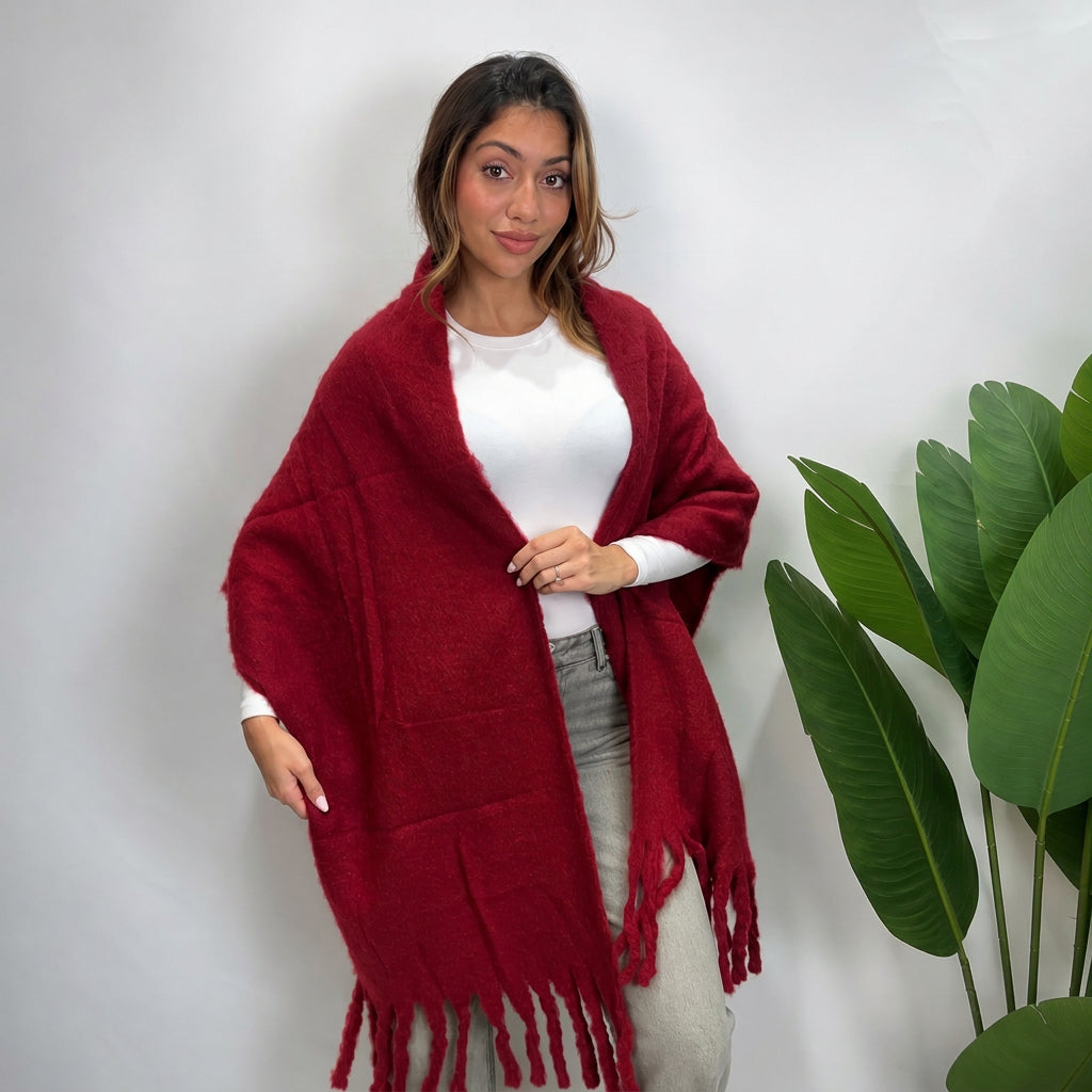 Woman wearing a burgundy brushed blanket scarf draped open over a white top with tassel ends
