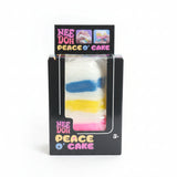 Rainbow layer cake slice sensory toy in black retail box, white squishy with blue, yellow and pink stripes