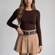 Camel box pleated mini skirt with a brown belt and gold square buckle, worn with a brown top