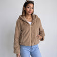 Camel faux fur hooded jacket with gold zip worn open over a white top and jeans