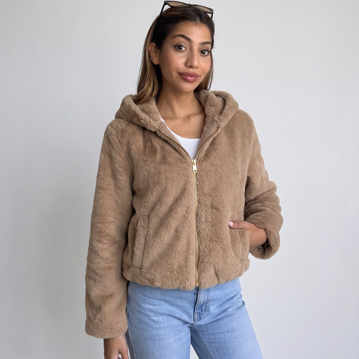 Camel faux fur hooded jacket with gold zip worn open over a white top and jeans