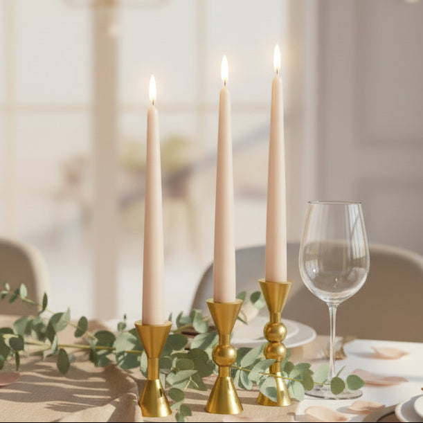 The squat gold trio lit at a laid table with eucalyptus and a stemmed wine glass