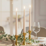 The squat gold trio lit at a laid table with eucalyptus and a stemmed wine glass