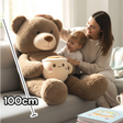 Brown bear with cream ear panels and a wide cream muzzle, its latte mug plush at rest in its lap