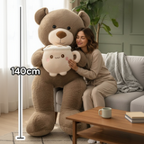 Mocha teddy bear hugging a latte mug plush beside a woman, with a 140cm line