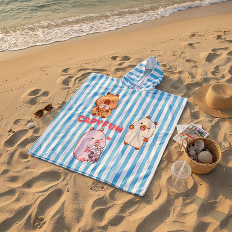 Blue and white striped capybara poncho towel with a bubble tea print flat lay on sand