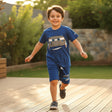 Child wearing a blue shirt with a car design, running on a wooden deck.