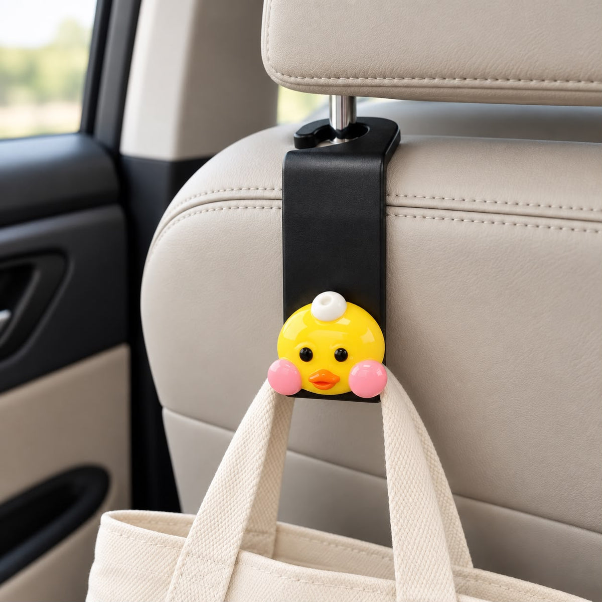 Car headrest hook with a yellow duck topper and pink cheeks holding a canvas tote bag