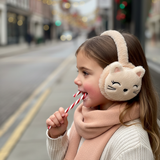Cream plush cat ear muffs with pointed ears worn by a girl outdoors in winter