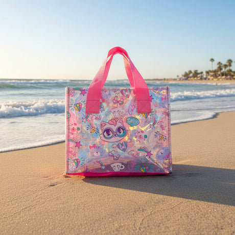 Holographic pink clear tote bag with cartoon cat faces and diamonds, standing on beach sand
