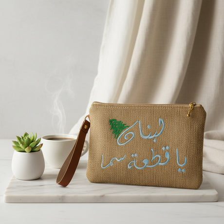 Jute zip pouch with the same Arabic phrase stitched in pale sky blue thread