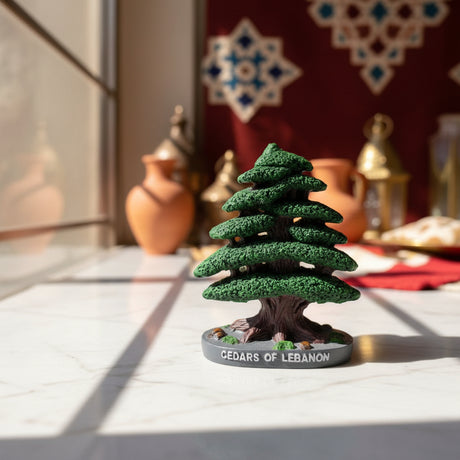Textured green cedar ornament on a round grey base reading Cedars of Lebanon