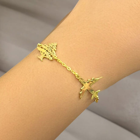 Gold cedar bracelet with airplane on a wrist against a neutral background