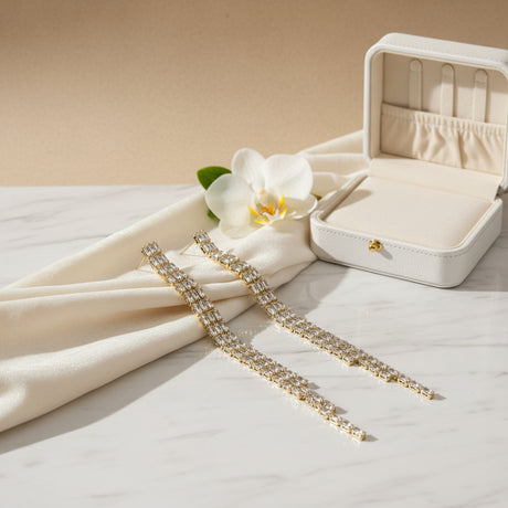 Pair of long, thin chain earrings with clear stones on a marble surface