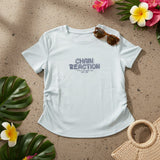 Light blue Chain Reaction tee flat lay with sunglasses and a straw bag
