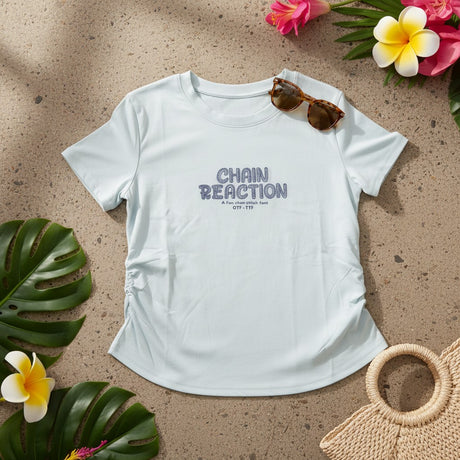 Light blue Chain Reaction tee flat lay with sunglasses and a straw bag