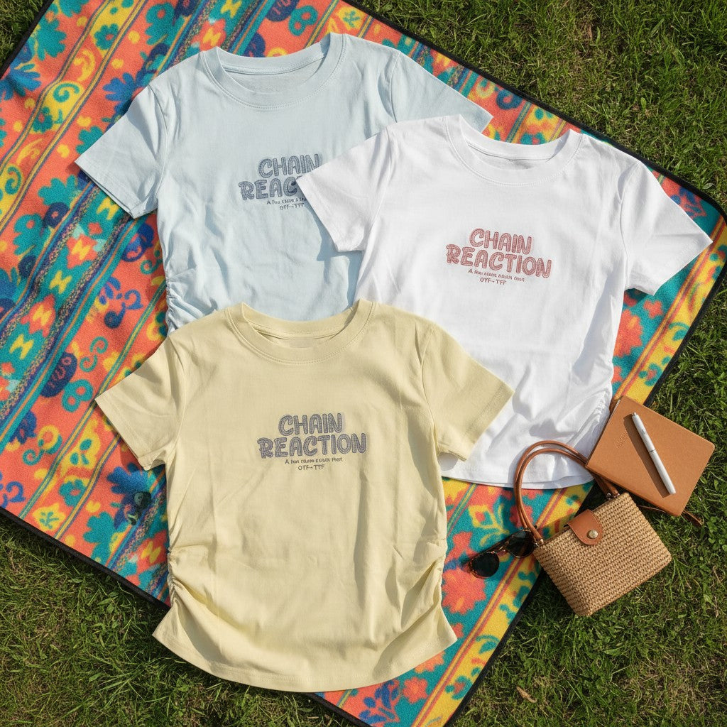 Three Chain Reaction slogan tees laid on a patterned picnic mat