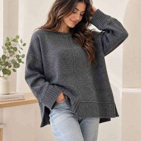 Charcoal grey oversized knit sweater with a centre front seam and ribbed hem, worn with light jeans
