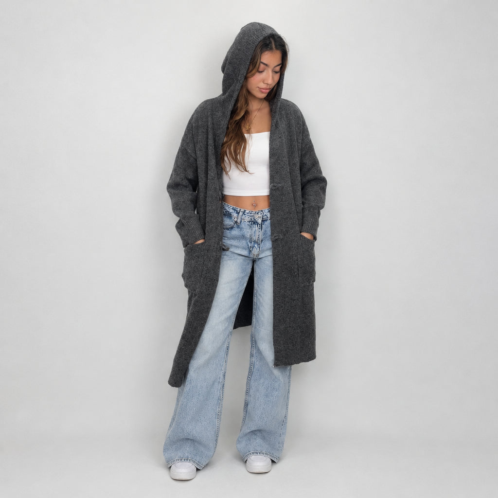 Charcoal long knit cardigan with the hood up, hands in the front pockets