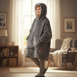Child wearing a charcoal hooded blanket with the hood up and a pocket motif