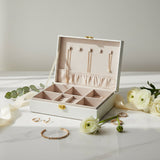 Cream jewelry box open to show five necklace hooks, an elastic pouch and ring slots