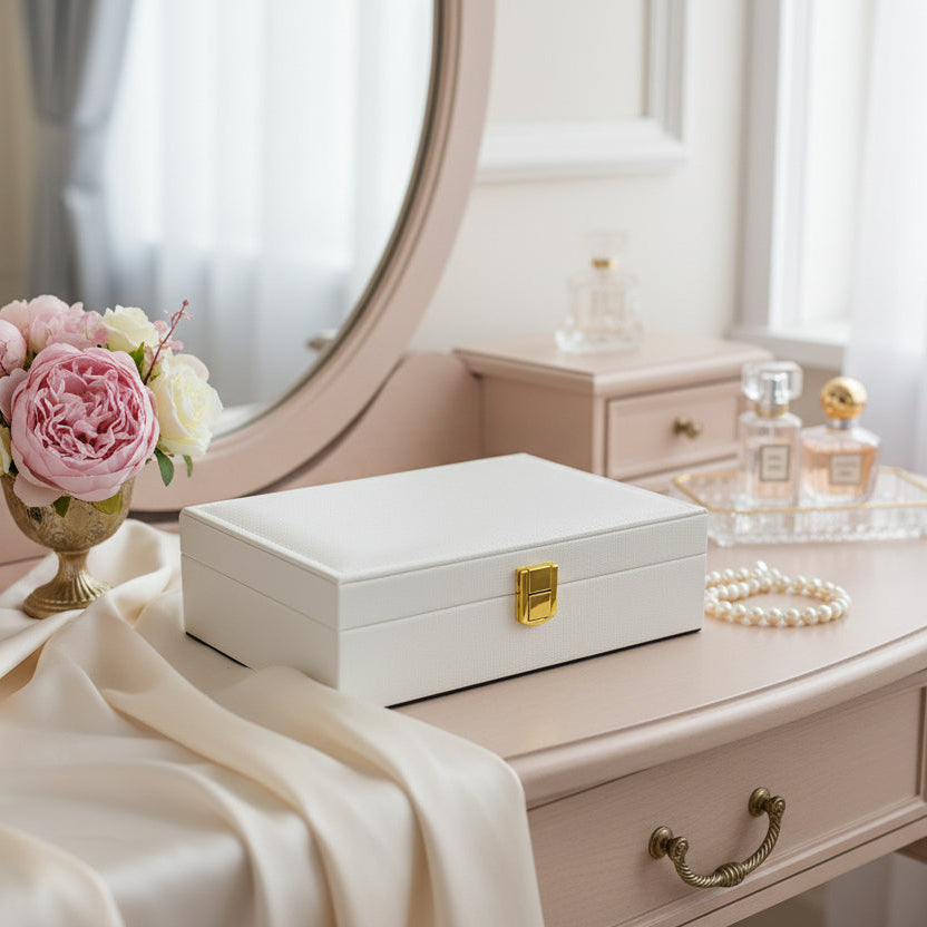 Cream jewelry box with an embossed croc texture and a gold flip clasp on a vanity