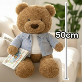 Curly teddy in a blue pinstriped shirt propped upright with an open picture book
