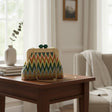 Handmade chevron clutch with a wooden frame and green clasp on a side table