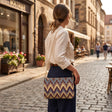 Handmade chevron ikat bag in plum, gold and blue worn over the shoulder on a gold chain