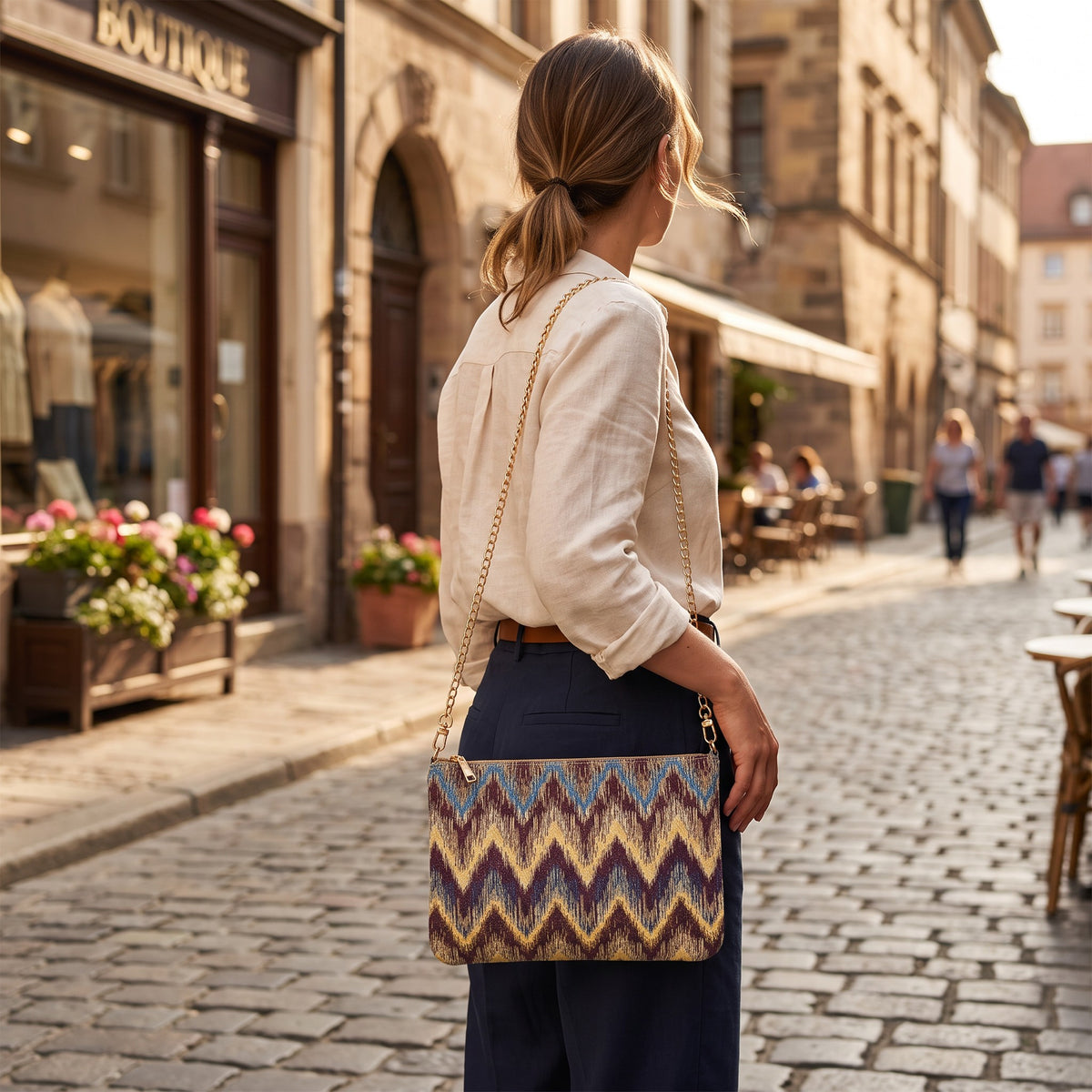 Handmade chevron ikat bag in plum, gold and blue worn over the shoulder on a gold chain