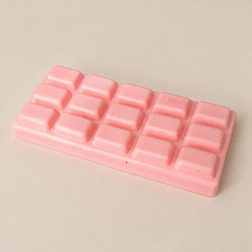 Pink chocolate bar squishy with fifteen raised squares on a soft beige backdrop