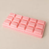 Pink chocolate bar squishy with fifteen raised squares on a soft beige backdrop