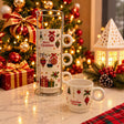 Four white ceramic Christmas mugs with ornament prints stacked on a chrome wire rack