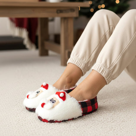 Fluffy white Santa face slippers with red and black check trim worn on a cream rug