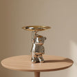 Standing chrome bear lifting one gold dish overhead with a watch and keys resting in it