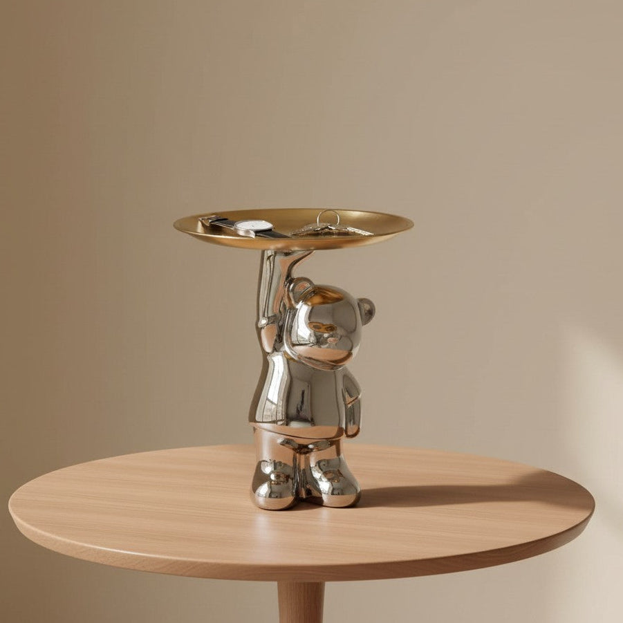 Standing chrome bear lifting one gold dish overhead with a watch and keys resting in it