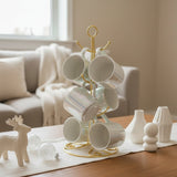White iridescent ceramic mugs hanging on a gold wire mug tree stand