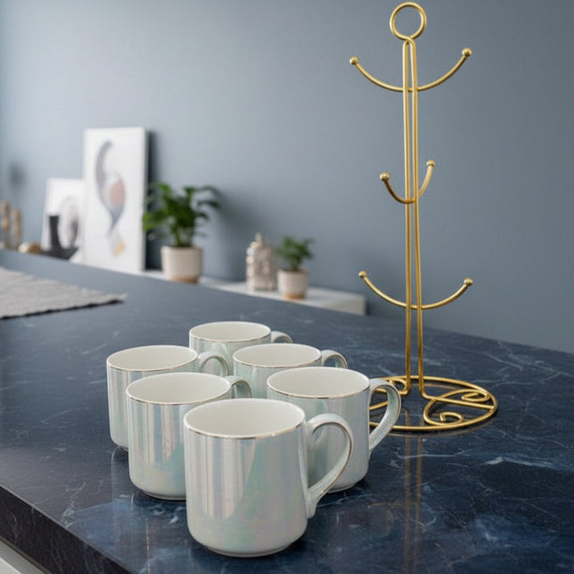 Six white iridescent ceramic mugs with gold rims on a navy marble counter